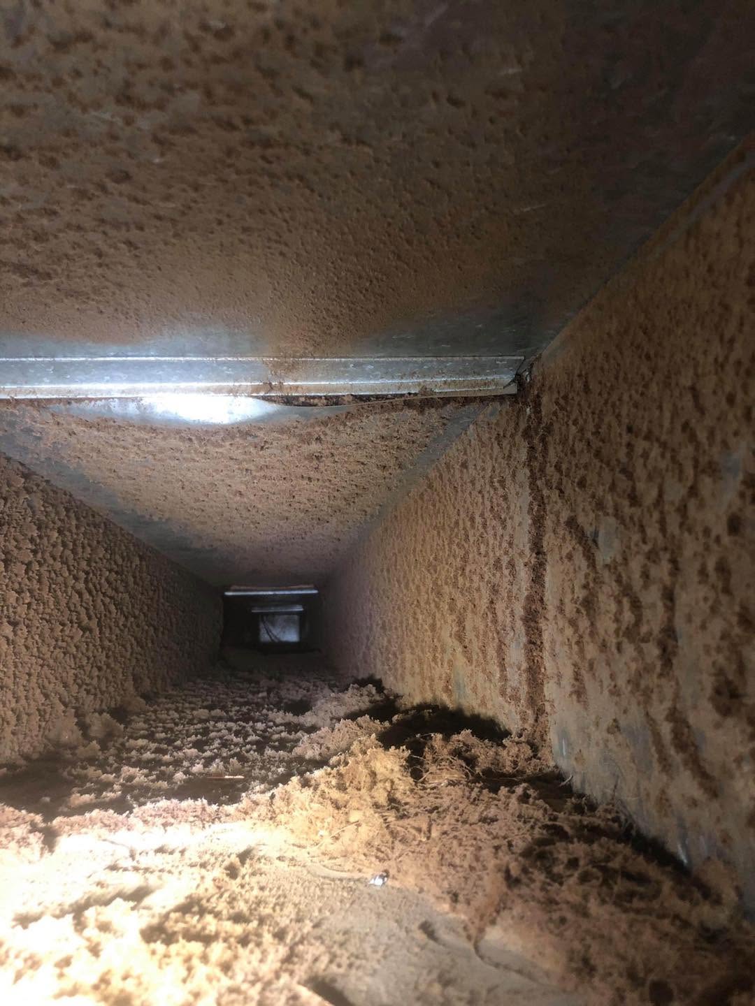 Interior of a residential duct heavily coated in dust before professional cleaning