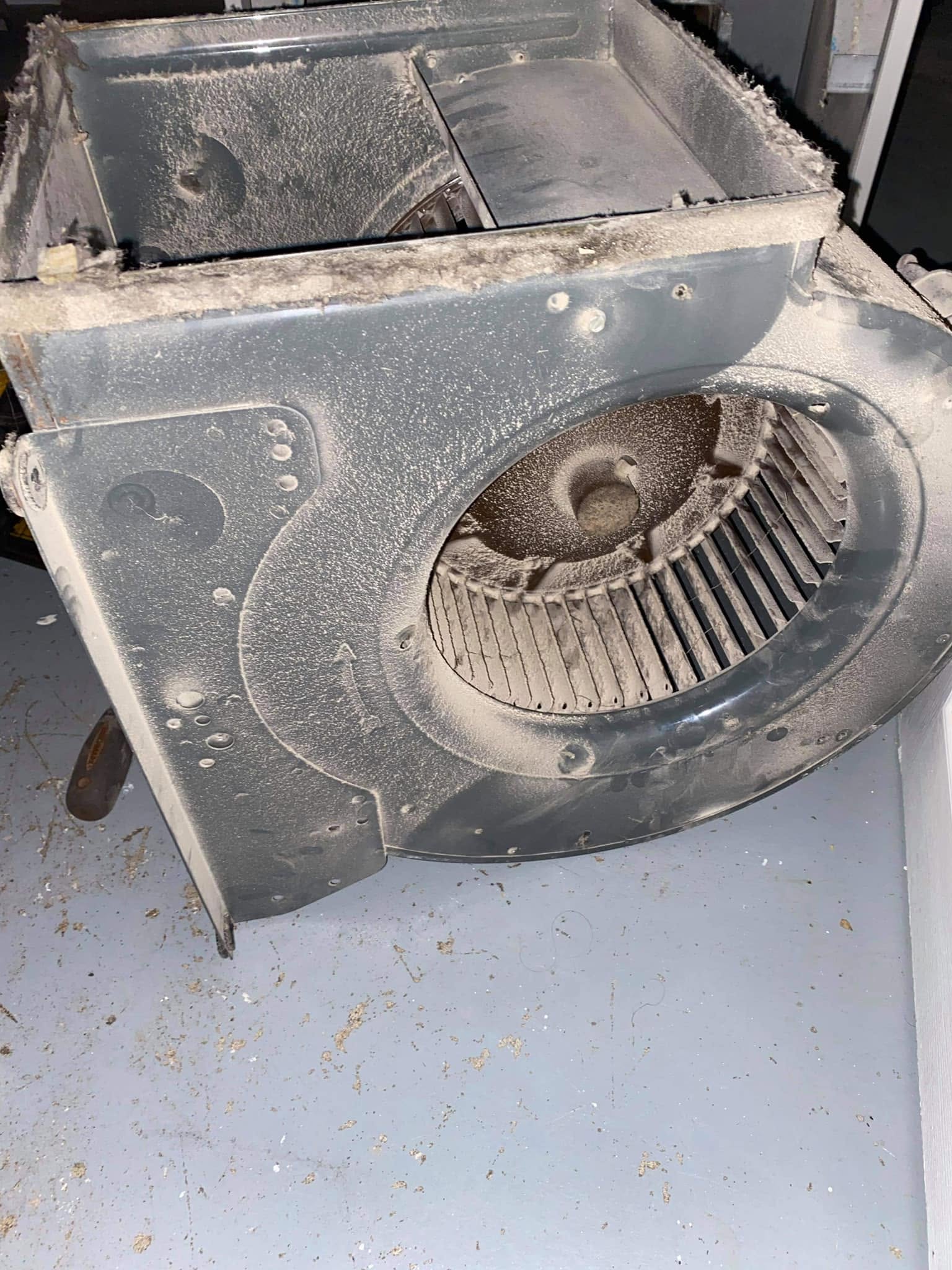 Blower wheel and housing coated in a thick layer of dust before cleaning