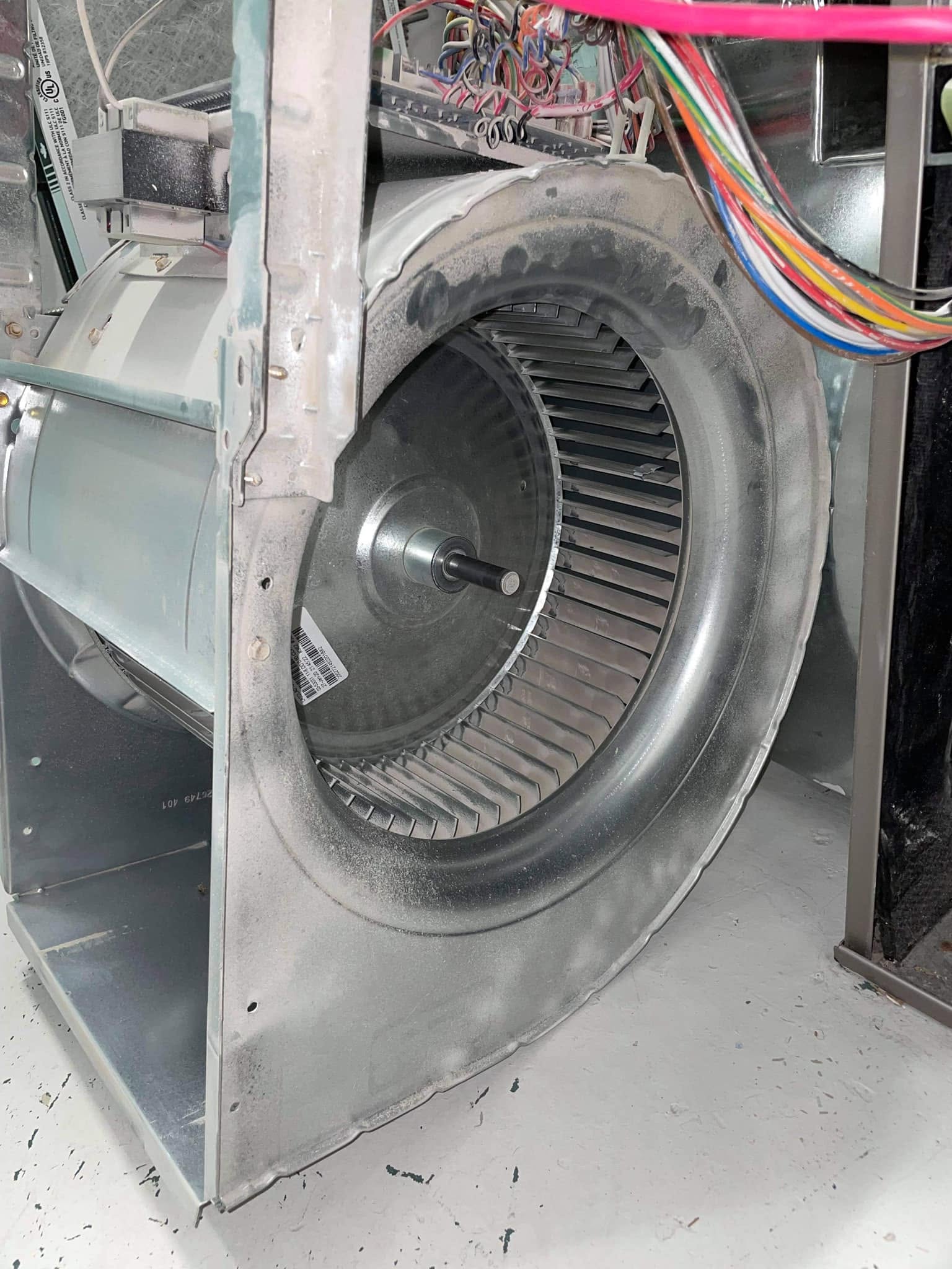 Furnace blower wheel coated in a thick layer of dust before professional cleaning.